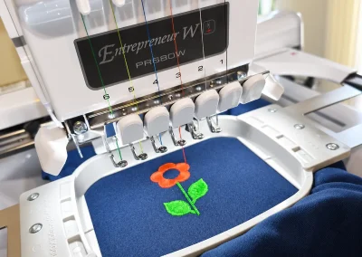 Broderie textile personnalisée en Ariège 1 Broderie d’une fleur colorée sur textile bleu à l’atelier DLB Design