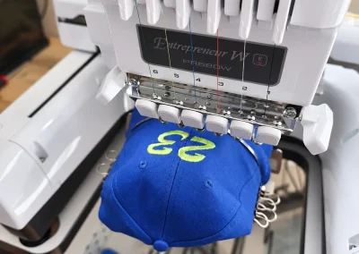 Broderie textile personnalisée en Ariège 4 Broderie du numéro 23 sur une casquette bleue à l’atelier DLB Design