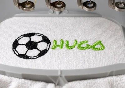 Broderie textile personnalisée en Ariège 11 Broderie du prénom Hugo accompagnée d’un motif de football